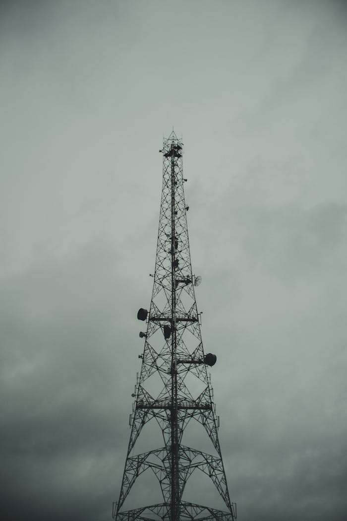 team-01 A vertical telecommunications tower with a monochrome backdrop of cloudy skies, captured in Nigeria.
