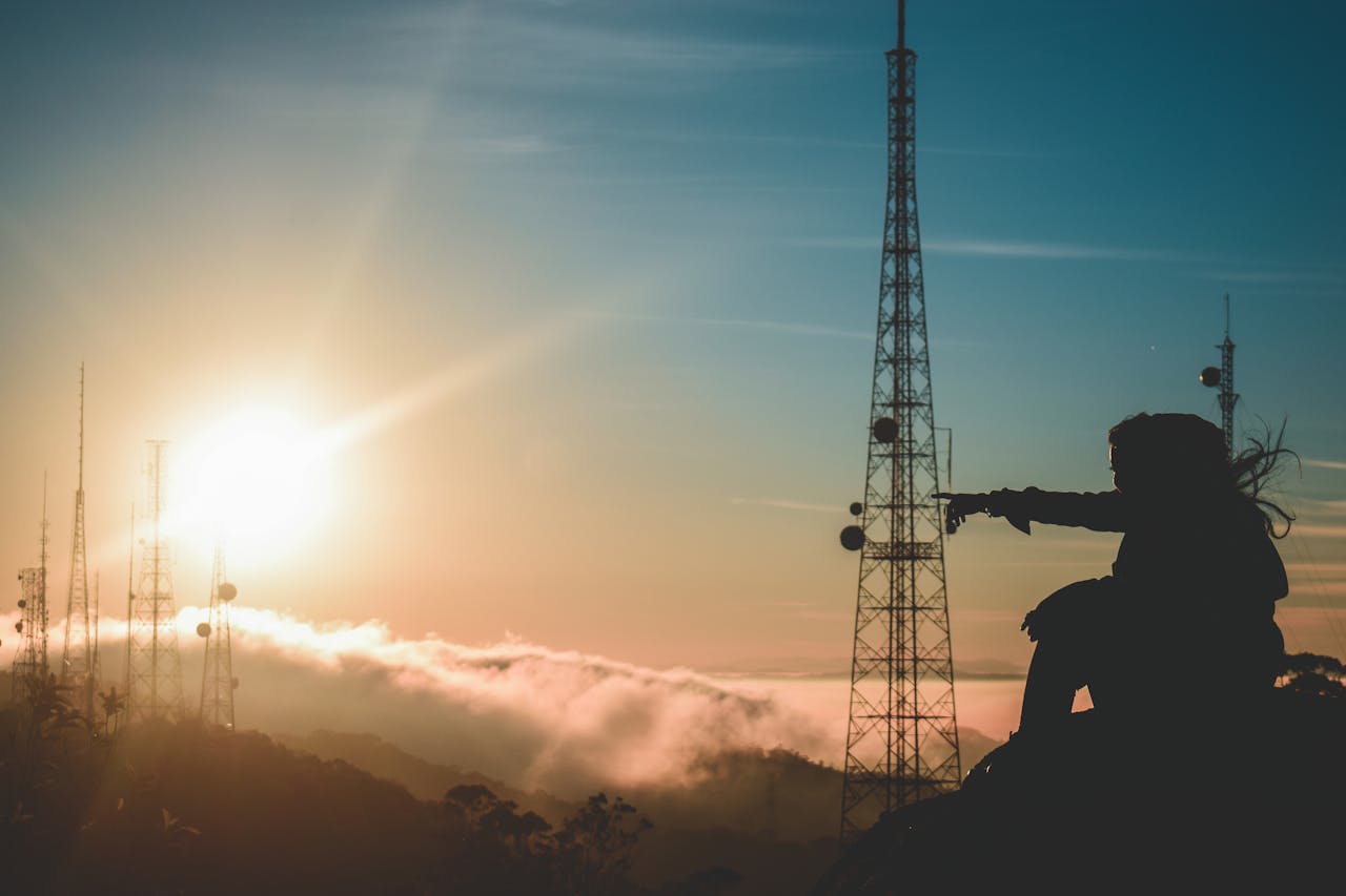 who-we-are A silhouette of a man pointing against a sunset with communication towers in São Paulo.